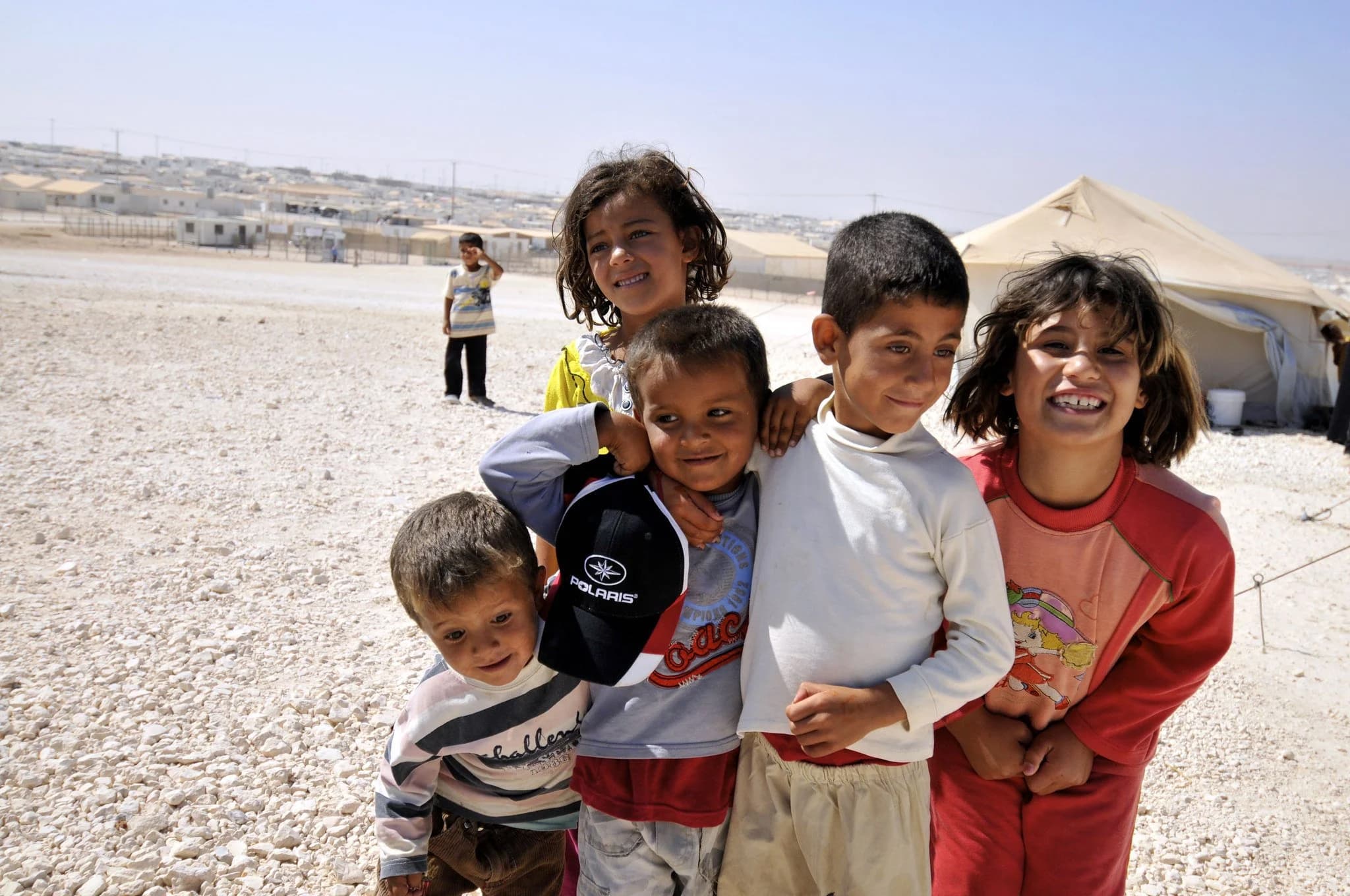 Smiling children standing together in a refugee camp