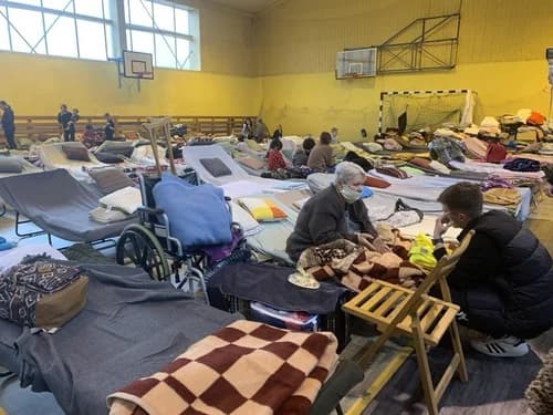 Кровати и раскладушки в спортзале, превращённом во временное убежище